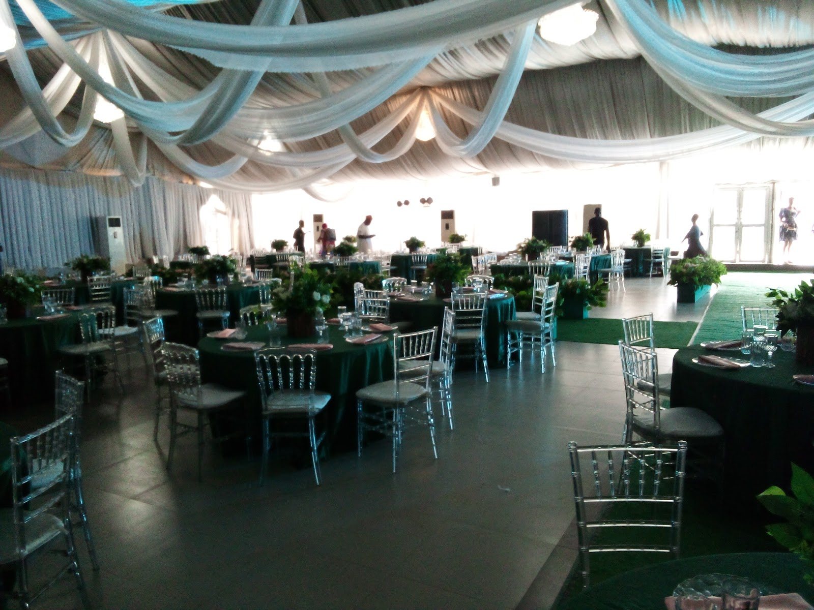 Dining set-up under pale teal drapes with green linen and tall air conditioners
